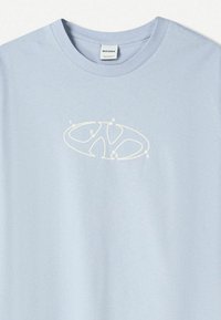 Light blue cotton t-shirt featuring a white logo design with numbered accents. Crew neck and short sleeves. Smooth texture.