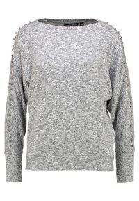 Harmaa pitkähihainen neule pehmeästä kankaasta. Siinä on koristeellisia metallinappeja olkaimuilla ja leveä, pyöreä pääntie.