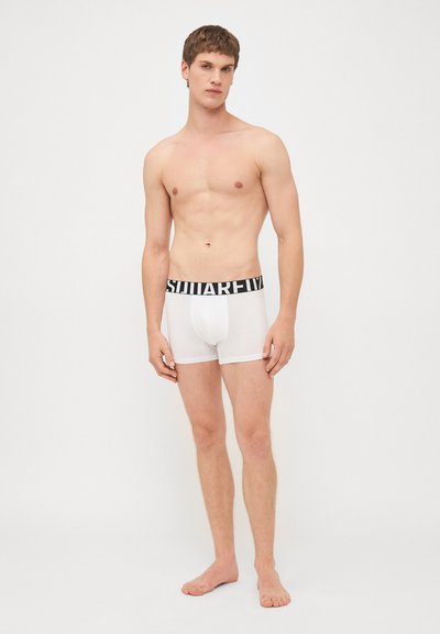 White cotton boxer briefs with a black elastic waistband featuring the brand name in bold. Smooth texture, fitted design.