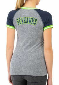 T-shirt gris en heather avec des manches raglan bleu marine, des accents verts et le mot "SEAHAWKS" en lettres bleues et jaunes au dos.