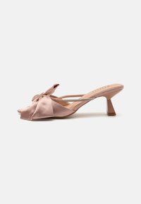 Rožinės satino slingback botai su dideliu kaspinu ir mažai blokine pakulne. Patogus dirželis, dekoruotas deimantais, ir atvira pėdos dalis.