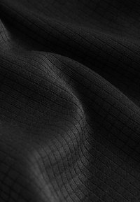 Tissu noir texturé présentant un motif de grille subtil, avec une surface lisse et un tombé léger, mettant en valeur la profondeur et le jeu de lumière.