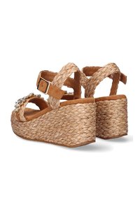 Sandalias de cuña con una plantilla de gamuza marrón, tacón de yute trenzado y adornos decorativos. Correa ajustable en el tobillo para un ajuste seguro.