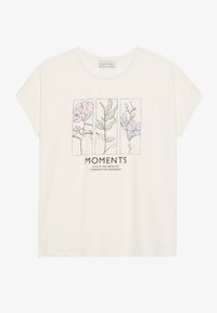 Kreem värvi lühikeste varrukatega T-särk, mis on valmistatud pehmest kangast ja millel on trükitud lillemuster pastelltoodetes koos tekstiga "MOMENTS" all.