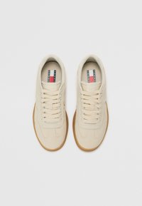 Paire de baskets couleur crème avec semelles en gomme et lacets, vues de dessus sur un fond blanc uni.