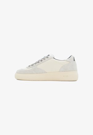 White sneaker with suede and fabric upper, round toe, lace-up front, and cream rubber sole. Features grey accents on the sides and heel.