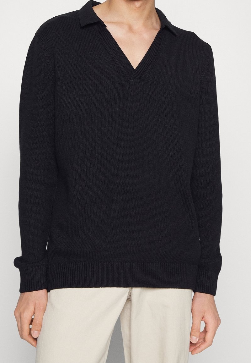 Maglione nero a maniche lunghe con scollo a V e colletto, texture a coste e vestibilità rilassata. Adatto per un look casual.