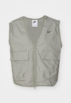 Ανοιχτό πράσινο γιλέκο Nike με V-λαιμό, λεπτομέρειες από δίχτυ, μπροστινό φερμουάρ και δύο ευρύχωρες τσέπες με καπάκι. Διαθέτει μικρό μαύρο λογότυπο στο στήθος.