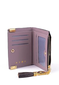 Fialová syntetická peněženka se zlatými detaily, s více sloty na karty, průhledným okénkem na identifikaci a zipem. Obsahuje třásničku a přívěsek s logem.