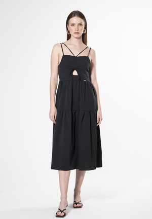 Schwarzes Midi-Kleid mit Spaghettiträgern, Cut-out-Schlüssellochdetail an der Vorderseite und gestuftem, gerafftem Rock. Glatte Textur, schlichtes Design.