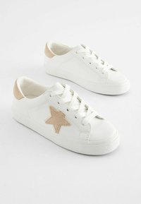 Sneakers bianchi in pelle con un accento a stella beige, suola in gomma testurizzata e tallone in beige chiaro a contrasto. Include lacci bianchi.