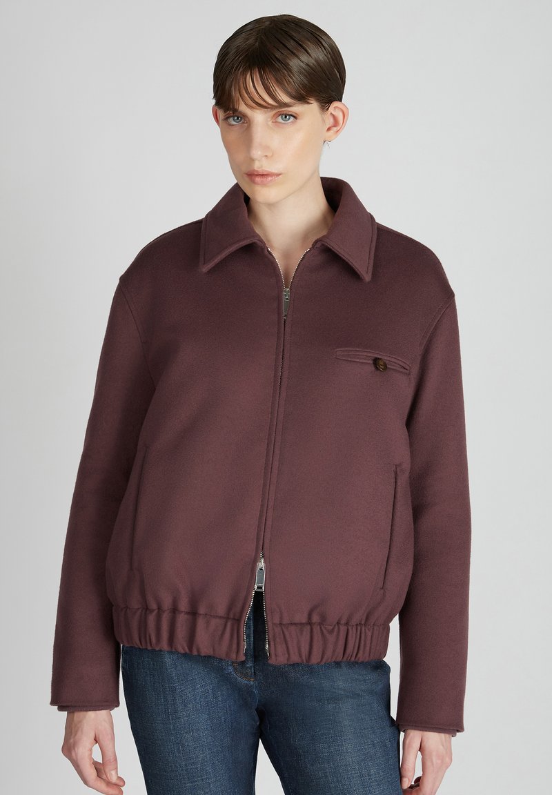 Bordeaux ritsjack met kraag, elastische tailleband en een borstzak met een knoop, gemaakt van een zachte, gestructureerde stof.