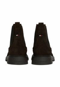 Stivali ankle in suede marrone con pannelli laterali elasticizzati, linguette posteriori e suole in gomma nera. Presentano un piccolo accento con logo rosso, bianco e blu.
