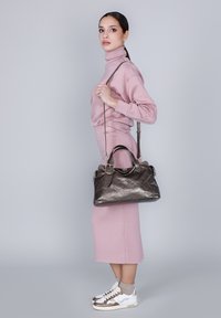 Borsa a mano in pelle grigio scuro con un motivo testurizzato, manici superiori e una tracolla; abbinata a un outfit rosa chiaro e scarpe da ginnastica bianche.