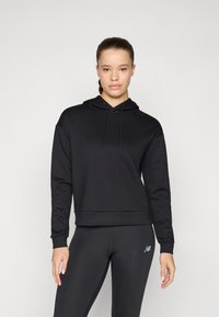 Svart hettegenser med avslappet passform, ribbede mansjetter og hem. Glatt stofftekstur med snorer i hetta. Kombinert med svarte leggings.