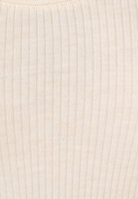 Tissu côtelé de couleur crème avec une texture douce et de fines lignes verticales. Pas de motifs ni d'ornements visibles.