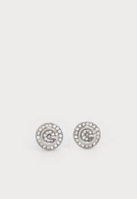 Silver stud earrings featuring a circular design with a prominent 'G' at the center, surrounded by small clear crystals.