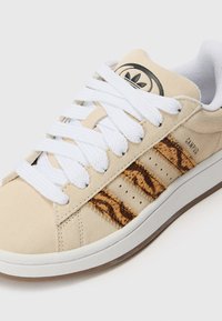 Beige semskede sneakers med hvite lisser, som har stripete faux dyremønster detaljer på siden og en teksturert gummisåle.