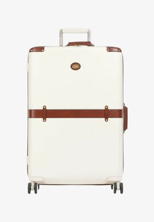 Maleta rígida de color crema con correas de cuero marrón, asa superior, asa lateral y cuatro ruedas negras sobre un fondo blanco.