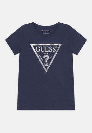 Mørkeblå T-shirt med korte ærmer med sølvtrekantet logo med teksten "GUESS U.S.A." og et stort spørgsmålstegn i midten.