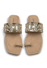 Infradito beige con una larga fascia impreziosita da grandi strass trasparenti e dorati. Suola piatta con un sottile design a loop per le dita.