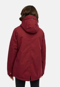 Körsbärsrandig hooded jacka med avslappnad passform, tillverkad av vattenavvisande material. Har en bakre ventil och tryckknappar på ärmarna.