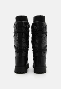 Botas tipo puffer negras con diseño acolchado, puño de punto elástico y suela de goma con dibujo texturizado para un mejor agarre.
