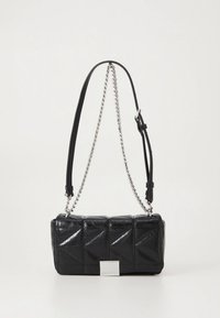 Czarna pikowana torebka o prostokątnym kształcie, z srebrnym łańcuszkiem i skórzanym paskiem oraz metalową tabliczką z logo na przedniej stronie.