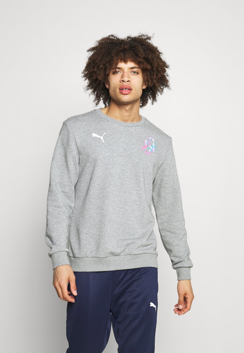 Sudadera de algodón gris con puños y dobladillo acanalados. Presenta el logo blanco de Puma en el pecho y un diseño gráfico colorido en el lado izquierdo.