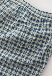 Tissu à carreaux bleu et beige avec motif de grille cousu et détail de taille élastique froncée.