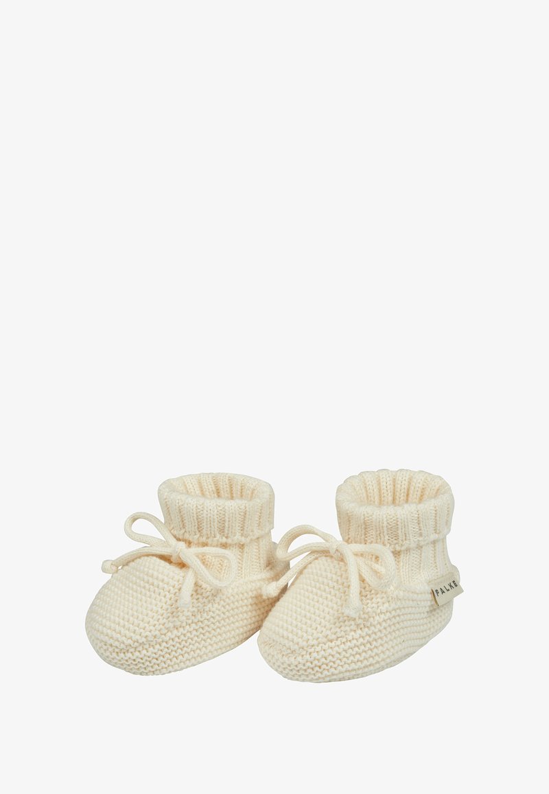 Scarpine per neonati lavorate a maglia in crema, con un polsino a coste e un dettaglio a fiocco. Texture morbida con punta arrotondata e una piccola etichetta sul lato.