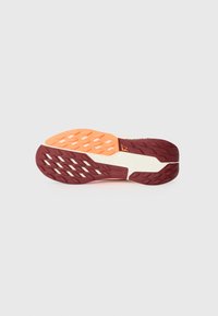 Semelle de chaussure de sport rouge et orange avec une surface texturée, présentant un motif de semelle prononcé et un intermédiaire blanc contrastant.