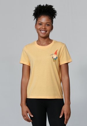 Gelbes Baumwoll-T-Shirt mit einem Gnom-Print auf der linken Brust. Kurze Ärmel, klassischer Rundhalsausschnitt und lockere Passform.