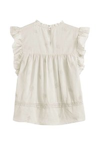 Blouse en coton blanc avec des manches volantes, motif floral brodé et fermeture en keyhole au dos. Texture douce et design à volants.