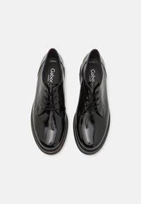 Sapatos de couro envernizados pretos com um acabamento suave, design de atacador e bico redondo. Apresentam uma palmilha acolchoada e sola baixa em borracha.