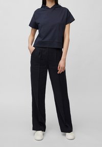 Sudadera recortada navy con un bolsillo frontal, combinada con pantalones de pierna ancha navy y zapatillas blancas, creando un look monocromático cohesivo.