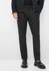 Grijze op maat gemaakte broek van textuurstof, met een slim fit, platte voorkant en knoopsluiting. Gecombineerd met elegante zwarte schoenen.