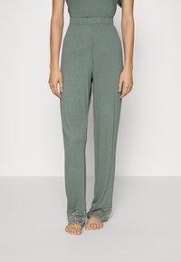 Lichtgroene, loszittende broek met een elastische tailleband en verfijnde kantdetails aan de onderranden. Zachte, gladde stoftextuur.