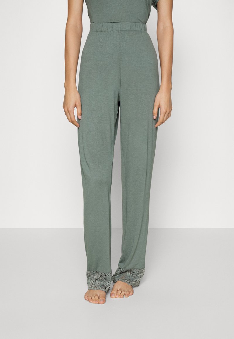 Lichtgroene, loszittende broek met een elastische tailleband en verfijnde kantdetails aan de onderranden. Zachte, gladde stoftextuur.