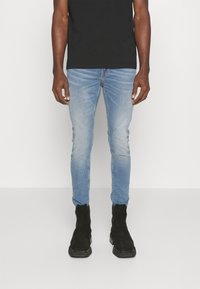Bleknade ljusblå skinny jeans med en lätt ombre-effekt, bärs med svarta mocka ankelskor och en fitted svart t-shirt.