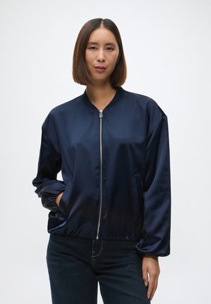 Jachetă bomber din satin bleu marin, cu fermoar în față, guler ribbed și manșete elastice. Dispune de buzunare laterale și o croială relaxată.