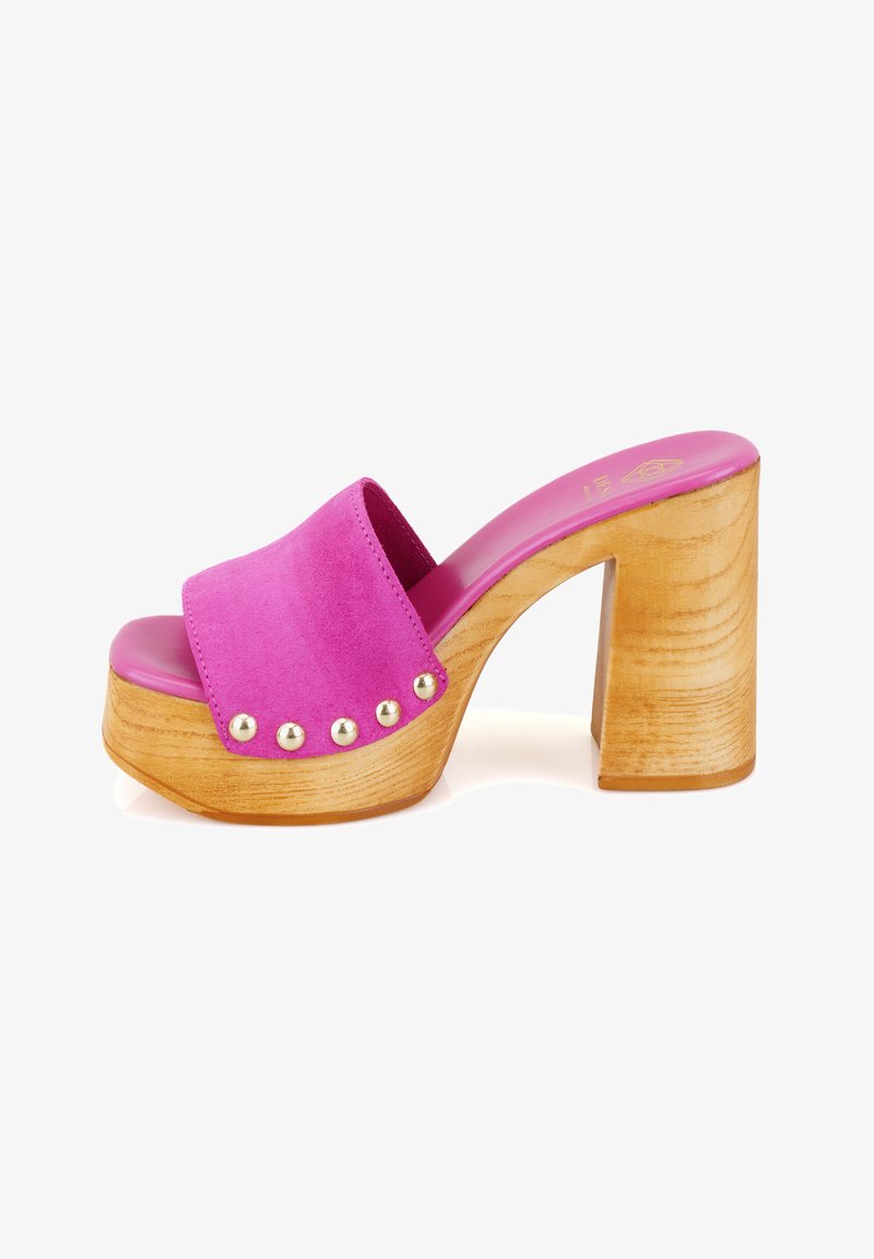 Roze suede hoge hakken sandaal met een houten blokhak en goudkleurige studs langs de rand. Gladde binnenzool in een heldere roze kleur.