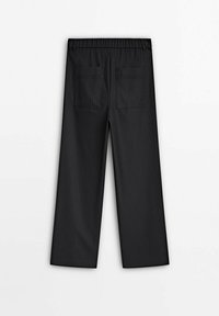 Pantalons noirs à rayures avec une coupe évasée et une taille élastique. Comprend deux poches arrière avec une texture lisse.