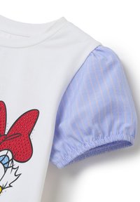 Camiseta blanca con un diseño de personaje de dibujos animados en rojo y negro, que cuenta con una manga acampanada de rayas en azul y blanco, con elástico fruncido.