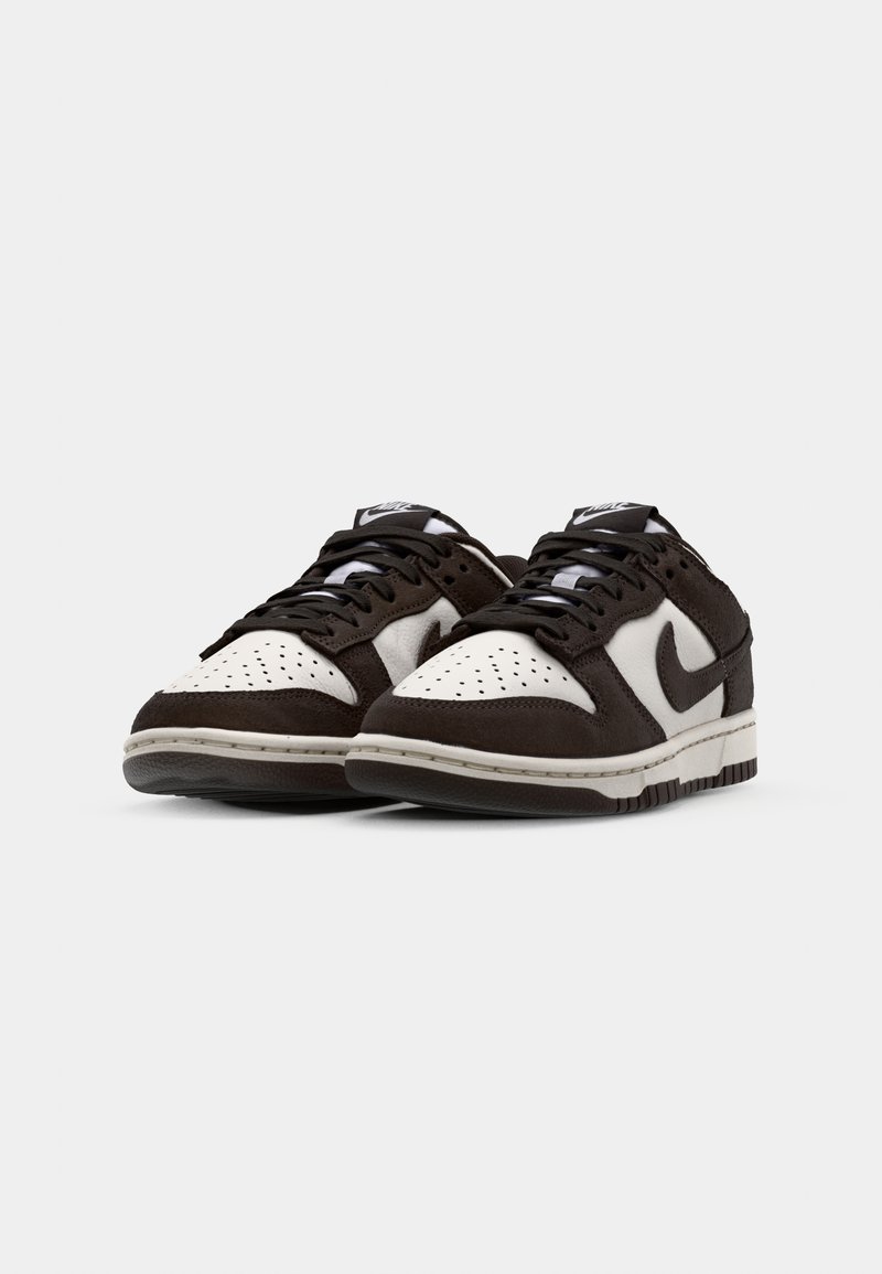 Sneakers Nike Dunk Low in suede e pelle marrone e bianca, con colletto imbottito, chiusura con lacci e punta perforata.