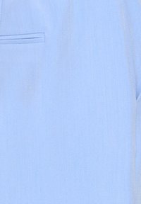 Lyseblåt stof med en glat tekstur og et subtilt skær. Indeholder en lomme med en synlig syning, der skaber et rent design.