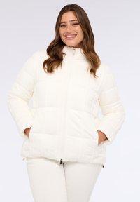 Giacca a vento imbottita bianca con colletto alto, chiusura con zip e tasche laterali. Presenta un sottile motivo a diamante e polsini elastici.