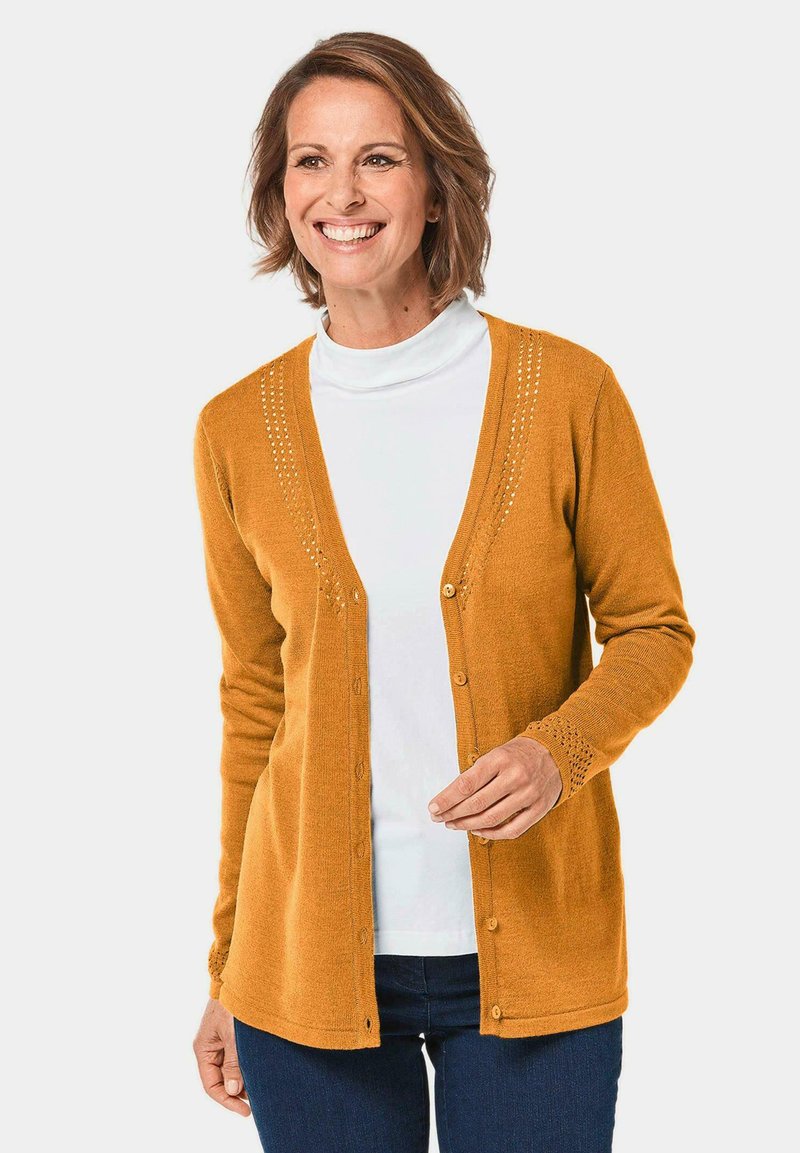 Senfgelber Cardigan mit durchgehender Knopfleiste, der ein strukturiertes Strickdesign und aufwendige Details am Halsauschnitt und an den Ärmeln aufweist.