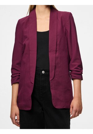 Frau trägt ein langärmeliges, pflaumenfarbenes Blazer mit gerafften Ärmeln über einem schwarzen Oberteil und hoch taillierten schwarzen Hosen.