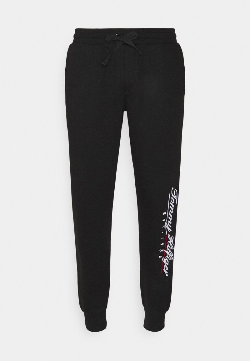 Svarta bomulls-joggbyxor med dragsko i midjan, avsmalnande ben och "Tommy Hilfiger"-logotyp med etableringsår tryckt i vitt och rött.